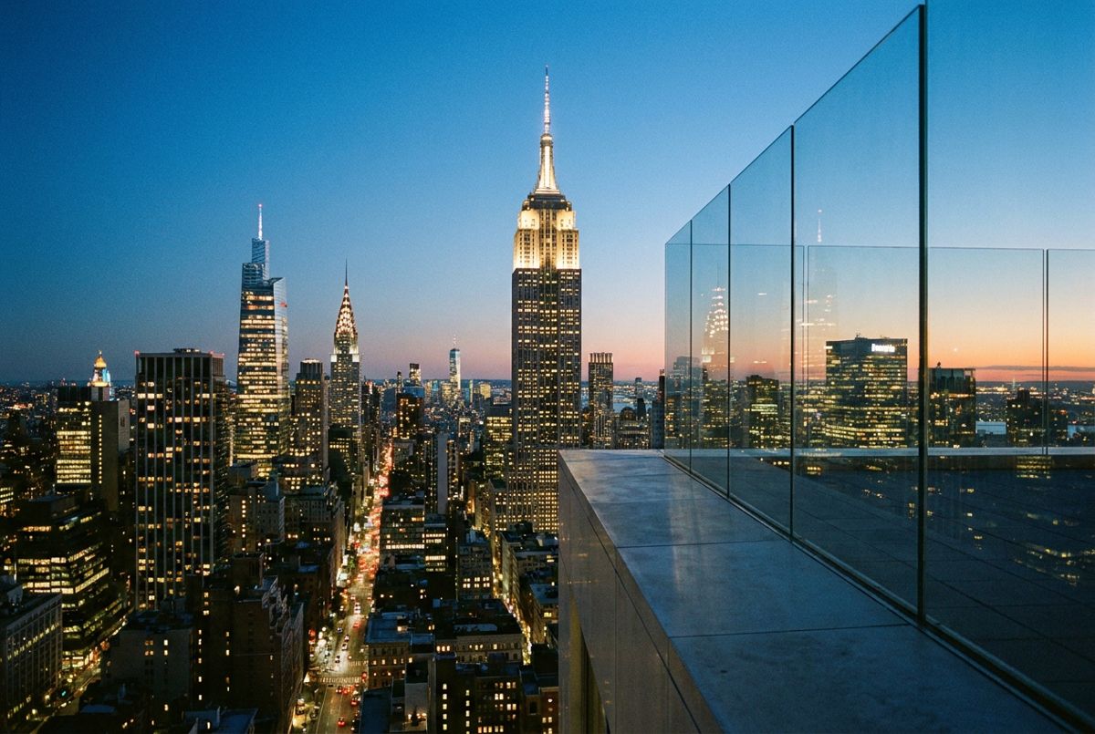 Empire State Building and Midtown towers glowing at dusk, seen from a high Manhattan observation deck