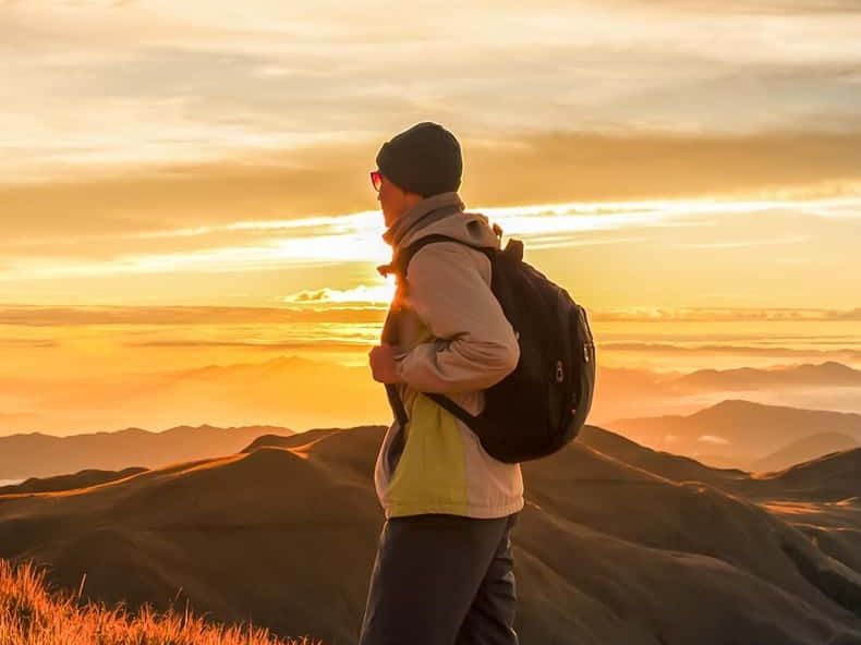 A hiker with a backpack watching the sunrise from Mount Batur
