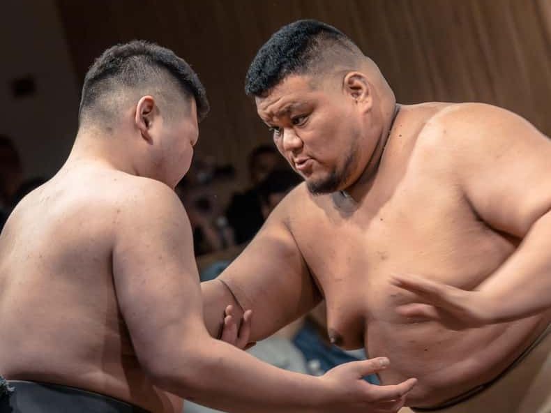 Two sumo wrestlers grappling in the ring during a show