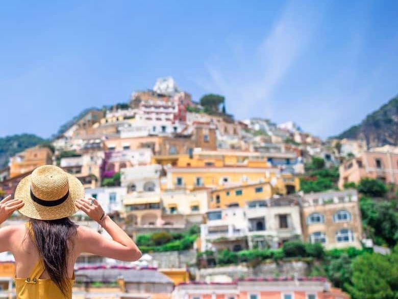 A woman in a straw hat looking up at the colorful houses of Positano