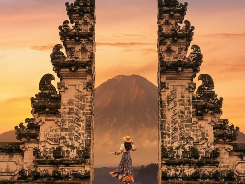A traveler standing between the stone gates of Lempuyang temple at sunset