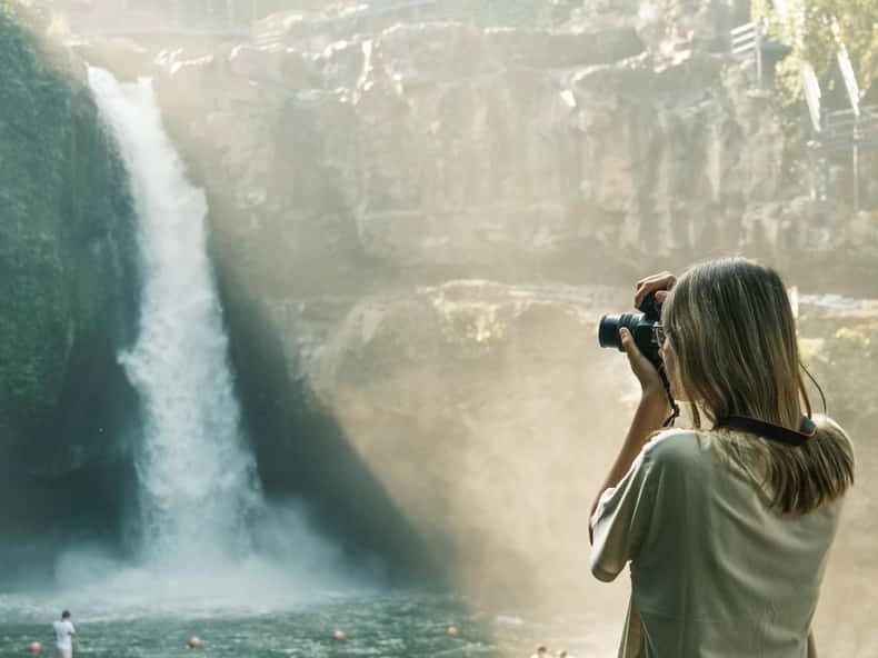 A visitor photographing Tegenungan waterfall near Ubud