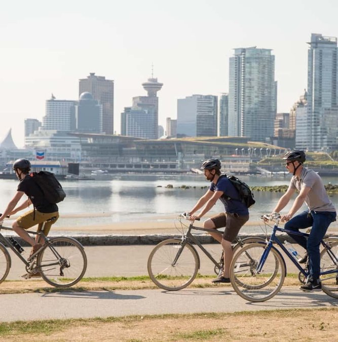 Cyclists on the seawall with the Vancouver skyline behind