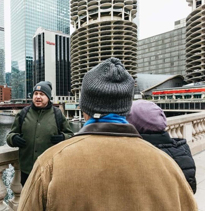Guide in a flat cap leading a walking tour through downtown Chicago