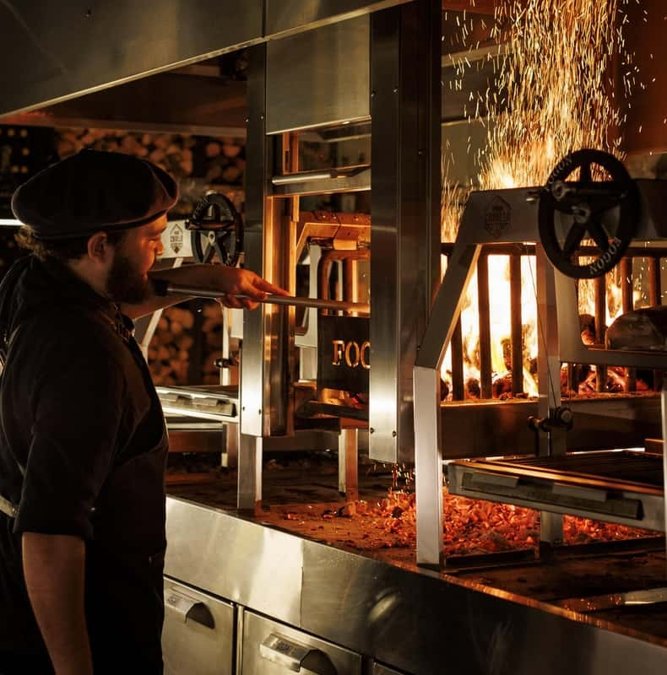 Chefs cooking over the open grill at Fogón Asado