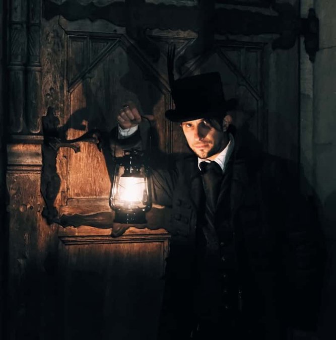 Guide in a top hat holding a lantern on a Krakow night walk