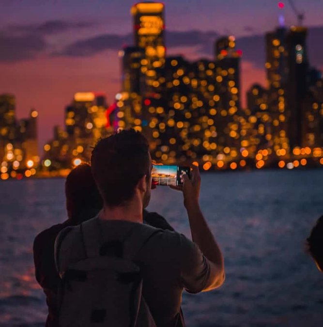 Passenger photographing the lit Chicago skyline from a night cruise