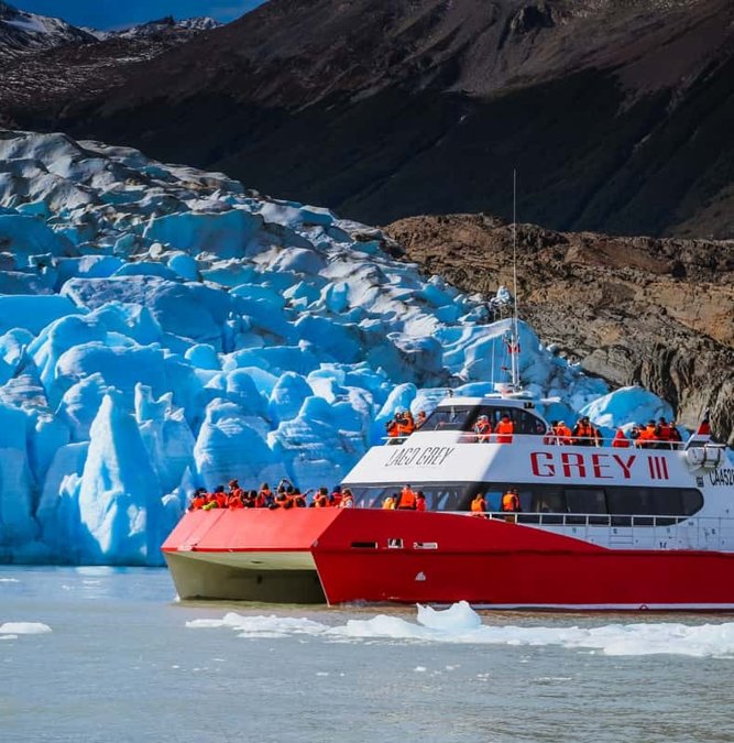 Red boat beside the blue ice wall of Grey Glacier