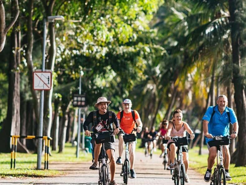 A group cycling along a tree-lined path in Singapore