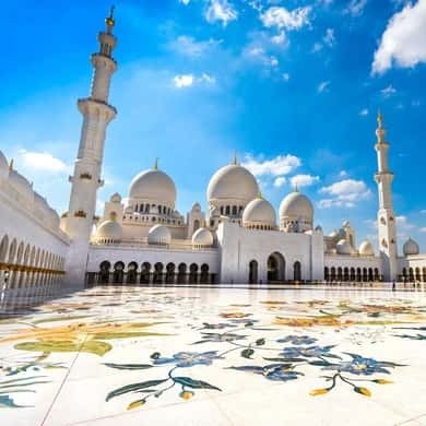 Courtyard of the Sheikh Zayed Grand Mosque under a blue sky