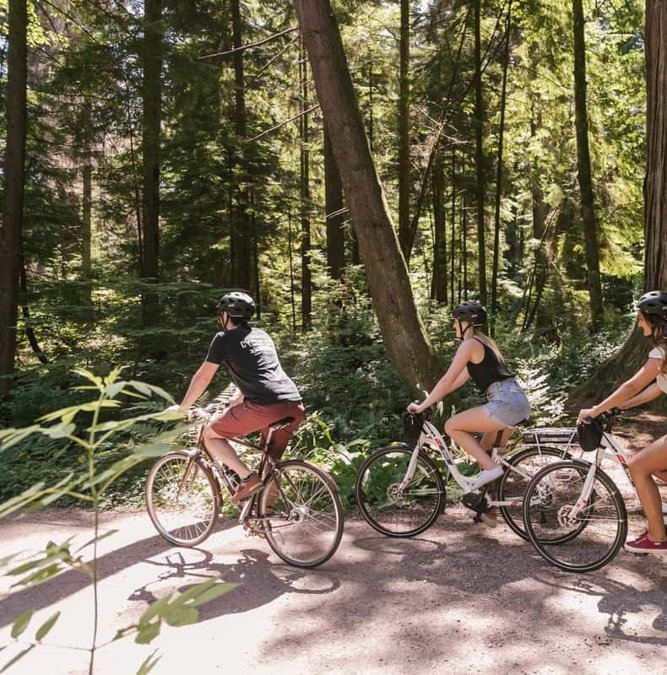 E-bike riders on a forest trail in Stanley Park