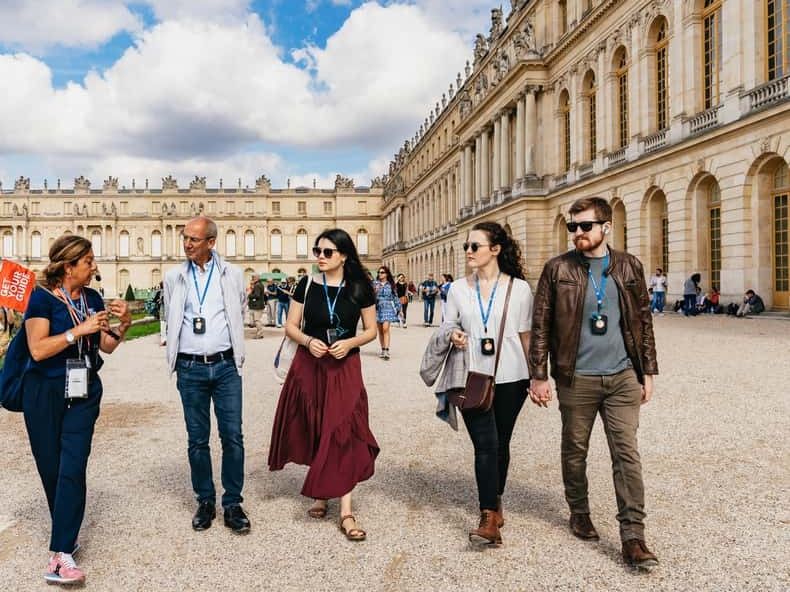 A small group with a guide crossing the courtyard in front of the Palace of Versailles
