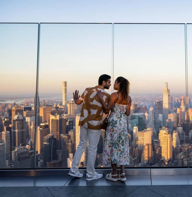 Couple on the Edge observation deck with the Manhattan skyline behind