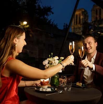 Couple toasting with champagne at a table on a Seine dinner cruise