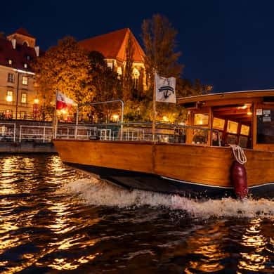 Illuminated boat cruising the Oder past the Wroclaw Old Town at night