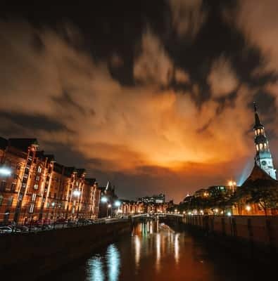 Hamburg harbor lit up at night under an orange sky