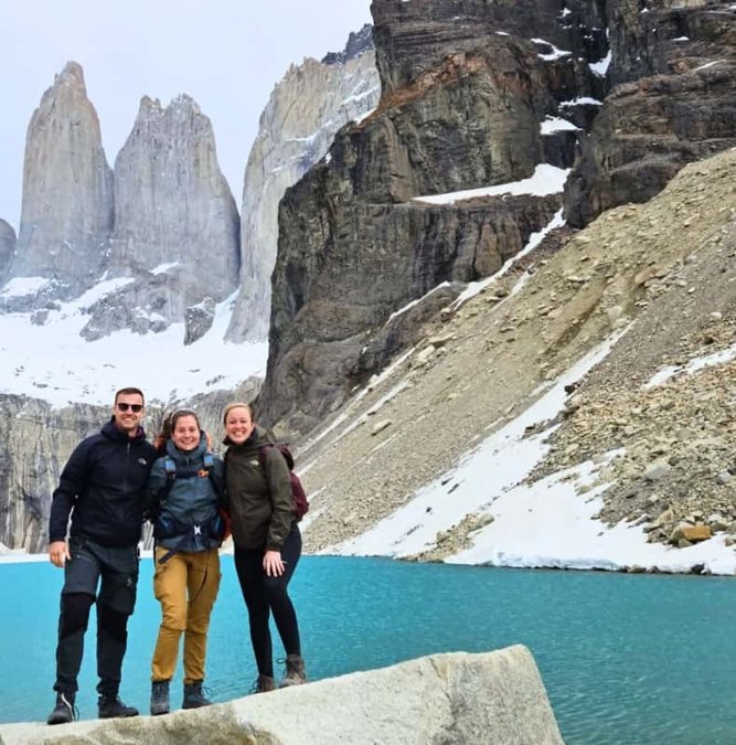 Hikers at the turquoise lake beneath the three granite towers