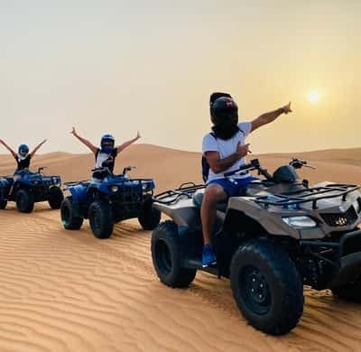 Quad bikers on the red dunes at sunset near Dubai