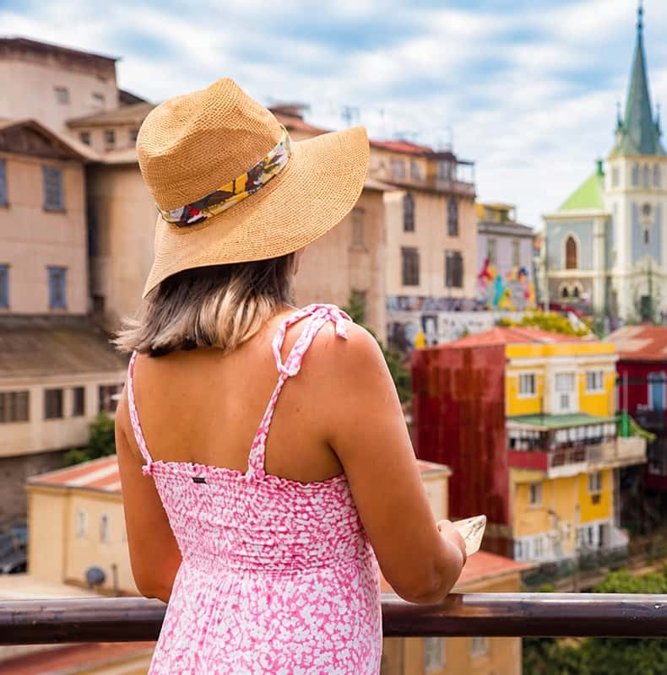 Traveler in a sun hat above the painted streets of Valparaíso