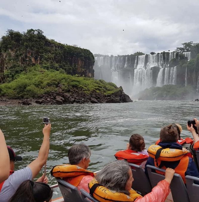 Passengers in life jackets on a boat below Iguazu Falls
