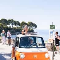 Orange electric mini car on a Riviera coastal road