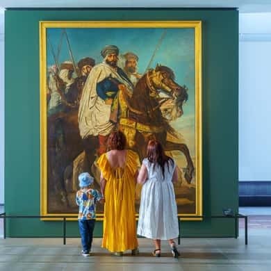 Visitors in front of a large painting inside the Louvre Abu Dhabi