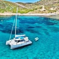 Catamaran anchored in a bright turquoise calanque