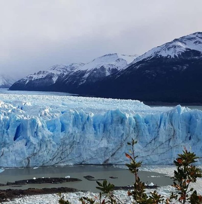 Blue ice front of Perito Moreno Glacier under mountains