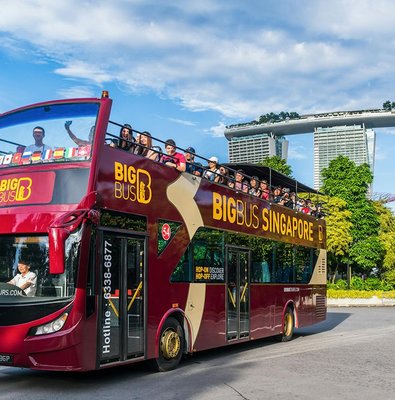 Tourists on a Singapore Hop-On-Hop-Off bus with Marina Bay Sands in the background.