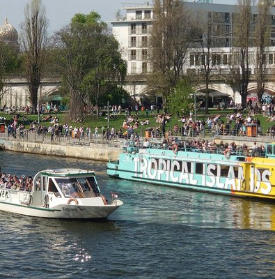 Sightseeing cruise boats on the River Spree in Berlin with people enjoying the view.