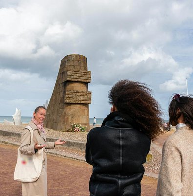 Guide explaining Omaha Beach Memorial to visitors in Normandy.