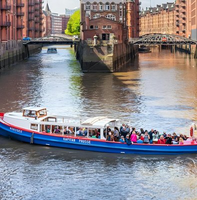 Harbor cruise boat with tourists on a canal in Hamburg's Speicherstadt district.