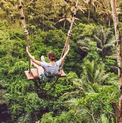 Person on a swing over lush jungle in Bali.