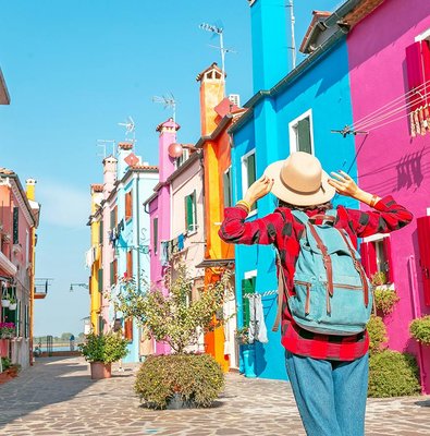 Woman exploring colorful buildings on Burano Island, Italy.