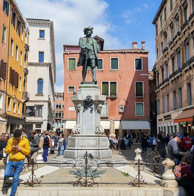 Statue of Carlo Goldoni in a bustling Venetian square, part of a guided culinary and sightseeing tour.