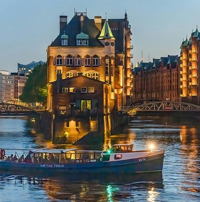 Evening cruise boat on illuminated canal in Hamburg's Speicherstadt district.