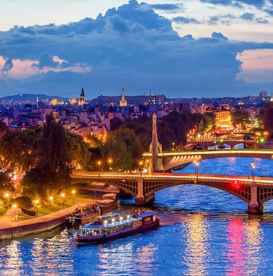 Paris skyline at night with Seine river and Paris En Scène Dinner Cruise boat.