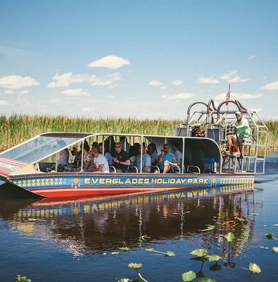 Airboat tour in Everglades Holiday Park with passengers exploring wetlands.