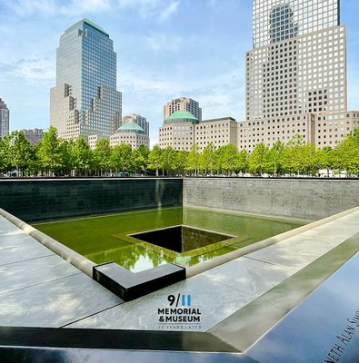 Reflecting pool at 9/11 Memorial in New York City with surrounding skyscrapers.