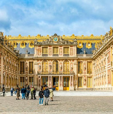 Palace of Versailles courtyard with visitors, showcasing ornate architecture and golden details.