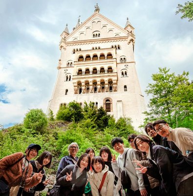 Tourists posing in front of Neuschwanstein Castle, Germany.