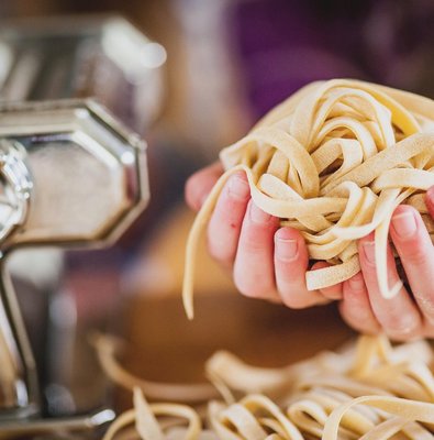 Hands holding a nest of freshly made tagliatelle